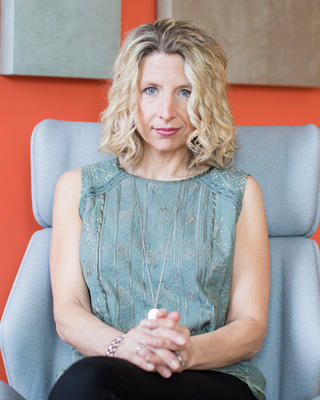 blonde woman sitting in a chair with her hands clasped in front of her