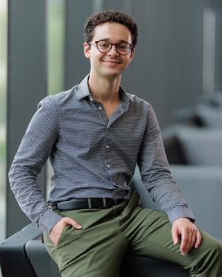 man sitting and smiling with his hand in one pocket