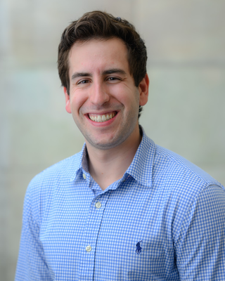 headshot of man in blue shirt smiling at the camera