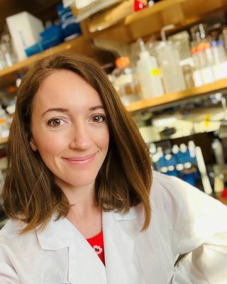 smiling woman with brown hair who is wearing a lab coat