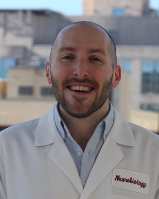 man in a white lab coat smiling at the camera