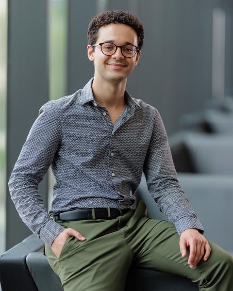 man sitting and smiling with his hand in one pocket